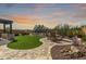 Expansive backyard featuring lush grass, a stone patio, an outdoor kitchen and decorative desert features at 30704 N 138Th Ave, Peoria, AZ 85383