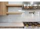 Close-up of a modern kitchen with stainless steel range hood, marble backsplash, and light wood cabinetry at 8110 E Saddle Horn Rd, Scottsdale, AZ 85255