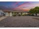 Backyard view of a ranch home with gravel, patio furniture and a large tree at sunset at 10027 W Concord Ave, Sun City, AZ 85351