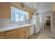 Kitchen with light wood cabinets, double sink, and a view into hallway at 10027 W Concord Ave, Sun City, AZ 85351