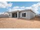 Exterior shot of the backyard featuring a covered patio with sliding doors and a blank canvas of dirt for landscaping at 11441 E Utah Ave, Mesa, AZ 85212