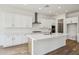Well-lit kitchen showcasing a central island, white cabinetry, and stainless steel range hood at 11441 E Utah Ave, Mesa, AZ 85212
