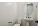 Stylish powder room with oval mirror, pedestal sink, and modern black fixtures for a sleek and contemporary design at 11441 E Utah Ave, Mesa, AZ 85212
