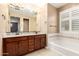 Bathroom featuring double vanity, soaking tub with tiled surround, and a large mirror at 15432 W Corrine Dr, Surprise, AZ 85379