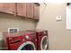 A laundry room with a red washer and dryer, and upper cabinets at 15432 W Corrine Dr, Surprise, AZ 85379