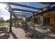 Comfortable outdoor patio with overhead beams providing shade for tables and chairs on the backyard lawn at 15432 W Corrine Dr, Surprise, AZ 85379