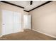 Carpeted bedroom with white closet doors, neutral walls, dark trim and ceiling fan at 21804 N 38Th Pl, Phoenix, AZ 85050