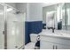 Modern bathroom with a glass-enclosed shower, white vanity, and blue wainscoting at 2560 E Thornton Ct, Gilbert, AZ 85297