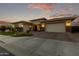 Stunning single-story home with a three-car garage and stone accents against a colorful dusk sky at 2560 E Thornton Ct, Gilbert, AZ 85297