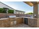 Outdoor kitchen with grill, built-in beverage cooler, and stone backsplash at 2560 E Thornton Ct, Gilbert, AZ 85297