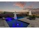 Beautiful pool and spa with stone decking and tranquil water features enhanced by the evening sky at 2560 E Thornton Ct, Gilbert, AZ 85297