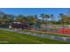 Tennis court with red surface and surrounding landscaping at 27831 N Makena Pl, Peoria, AZ 85383