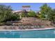 Community swimming pool with a slide and sun loungers, surrounded by stone walls and mature trees at 330 S San Fernando Ln, Casa Grande, AZ 85194