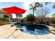 Stunning backyard pool features rock waterfall, red umbrella, and mature landscaping at 3559 E Bridgeport Pkwy, Gilbert, AZ 85295