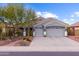 Single-story house with gray exterior, three-car garage, and desert landscaping at 12522 W Llano Dr, Litchfield Park, AZ 85340