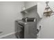 Bright laundry room with modern washer and dryer and overhead shelving at 17669 W Daley Ln, Surprise, AZ 85387