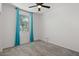 A neutral-toned bedroom with plush carpet, a window with blue curtains and a modern ceiling fan at 26706 N 174Th Ln, Surprise, AZ 85387