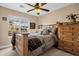 Bedroom with earth-toned bedding, wood furniture, ceiling fan, and bright window at 3000 E Tulsa St, Gilbert, AZ 85295