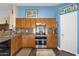 Galley kitchen with stainless appliances, wood cabinets, stone countertops, and blue accent wall at 3000 E Tulsa St, Gilbert, AZ 85295