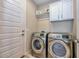 Laundry room with stainless steel washer and dryer, storage cabinet and door at 30343 N 130Th Dr, Peoria, AZ 85383