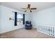 Bedroom with large window, ceiling fan, crib, and recliner at 4749 E Evergreen St, Mesa, AZ 85205