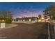 Expansive single-story home with detached garage, circular driveway, white fence, and mature trees at twilight at 5249 E Thunderbird Rd, Scottsdale, AZ 85254