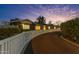 A winding driveway leads to this home that features a quaint white fence and mature landscaping at twilight at 5249 E Thunderbird Rd, Scottsdale, AZ 85254