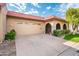 Front view of a tan house with a two-car garage and manicured lawn at 7837 E Crestwood Way, Scottsdale, AZ 85250