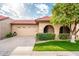 Tan stucco house with a tiled roof, attached garage, and lush landscaping at 7837 E Crestwood Way, Scottsdale, AZ 85250