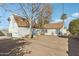 Exterior shot of a charming white stucco home and dirt backyard featuring a mature tree and palm tree at 2209 E Weldon Ave, Phoenix, AZ 85016