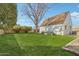 Backyard features lush green grass, a brown roof home, a large tree, bushes, and brick trim at 2209 E Weldon Ave, Phoenix, AZ 85016