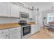 White kitchen with stainless steel appliances and view into dining area at 22992 W Lasso Ln, Buckeye, AZ 85326