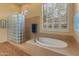 Relaxing bathroom with soaking tub, glass block shower, and neutral tile flooring at 2310 W Hazelhurst Dr, Anthem, AZ 85086