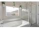 Well-lit bathroom featuring a soaking tub, a glass-enclosed shower, and greenery at 3711 E Sandy Way, Gilbert, AZ 85297