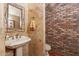 Small bathroom with pedestal sink and exposed brick feature wall at 5113 W Arrowhead Lakes Dr, Glendale, AZ 85308