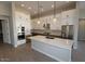 Spacious kitchen featuring white cabinetry, stainless steel appliances, a large island, and modern pendant lighting at 6818 N 190Th Ave, Waddell, AZ 85355