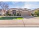 Single-story home with tan exterior, landscaped yard, and a two-car garage at 8687 E Tuckey Ln, Scottsdale, AZ 85250