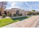 Tan colored single story home with well manicured landscaping and a large driveway at 8687 E Tuckey Ln, Scottsdale, AZ 85250