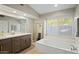 Elegant bathroom with double vanity, soaking tub, and large window at 9230 N 104Th Pl, Scottsdale, AZ 85258