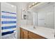 Clean bathroom with a wood vanity, a white countertop, large mirror, and a blue and white shower curtain at 2338 N 112Th Ln, Avondale, AZ 85392