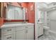 Bright bathroom with a red accent wall, a vanity with storage and white tile in shower at 4301 E Montecito Ave, Phoenix, AZ 85018