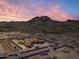 Breathtaking aerial view of the home in construction, nestled against a mountain backdrop and colorful sunset at 6109 E Maverick Rd, Paradise Valley, AZ 85253