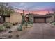 Modern home exterior with desert landscaping and a three-car garage at 10598 E Fernwood Ln, Scottsdale, AZ 85262