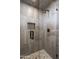 Shower with glass enclosure, pebble floor, and grey tile at 10598 E Fernwood Ln, Scottsdale, AZ 85262