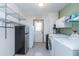 Bright laundry room featuring tile floors, storage shelving, refrigerator and laundry machines at 14019 N 51St Dr, Glendale, AZ 85306