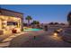 Night view of backyard oasis with pool, patio furniture, and desert landscaping at 15725 W Linksview Dr, Surprise, AZ 85374