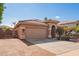 Tan house exterior with a two-car garage and a gravel pathway at 15839 W Calavar Rd, Surprise, AZ 85379