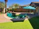 Relaxing pool area with green lawn, striped umbrella, and waterfall feature at 21362 E Puesta Del Sol Rd, Queen Creek, AZ 85142