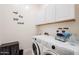 Modern laundry room with front-load washer and dryer, overhead cabinets, and stylish decor at 23933 N 167Th Ln, Surprise, AZ 85387