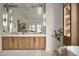 Bright bathroom with marble countertops, wood cabinets and large mirrors with decorative light fixtures at 27545 N 97Th Pl, Scottsdale, AZ 85262